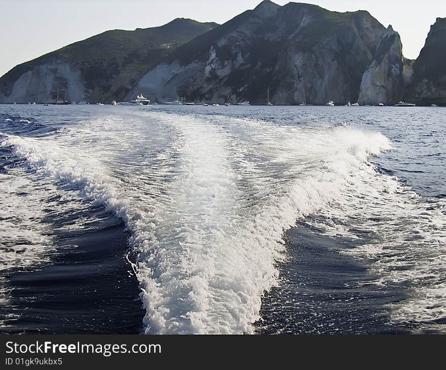 Wake of the boat with sea cliff