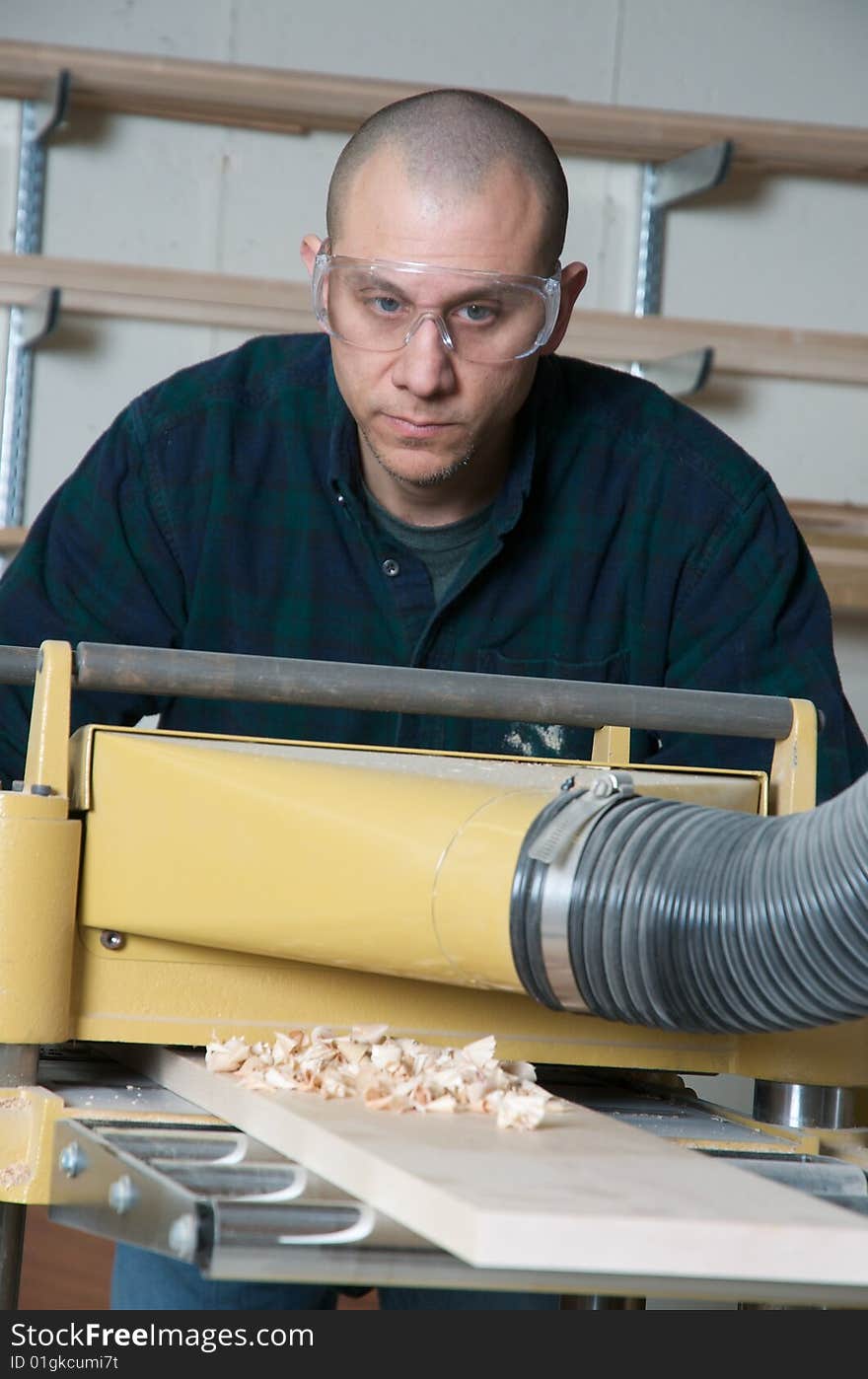 A wood worker using power tools in a work shop