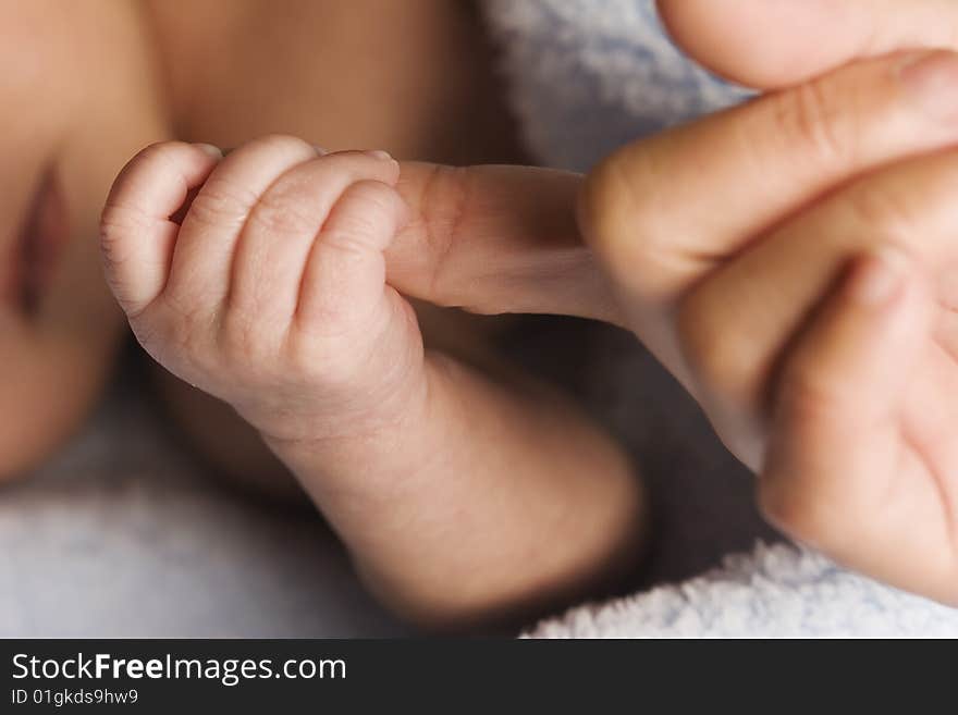 Close-up of baby's little hand holding mom's finger.