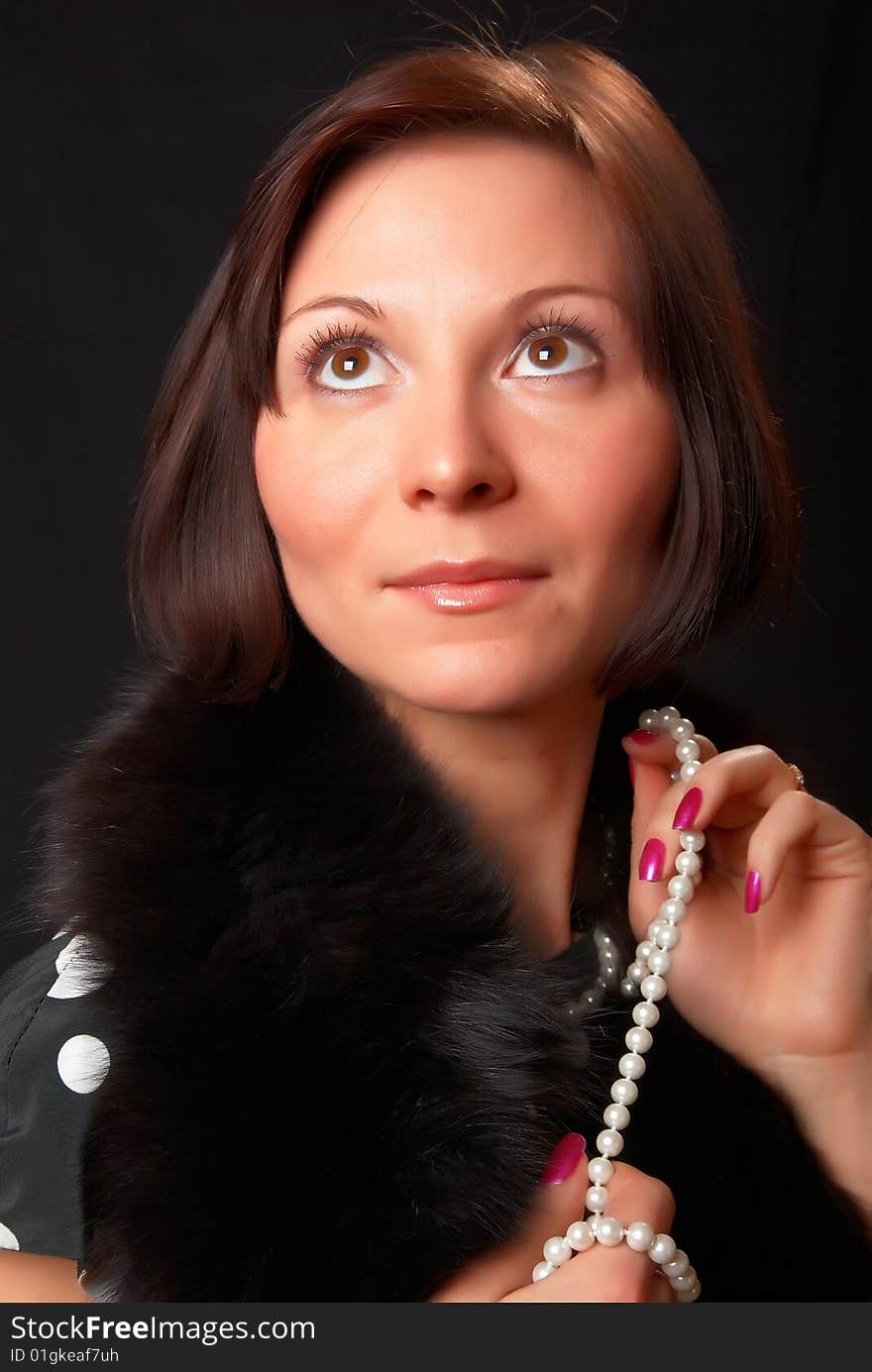 Portrait of a young lady with a pearl necklace in a hands.