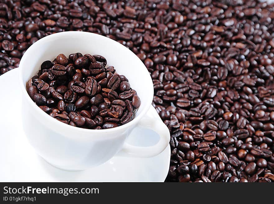 Coffee grains in a white cup on a background coffee grains