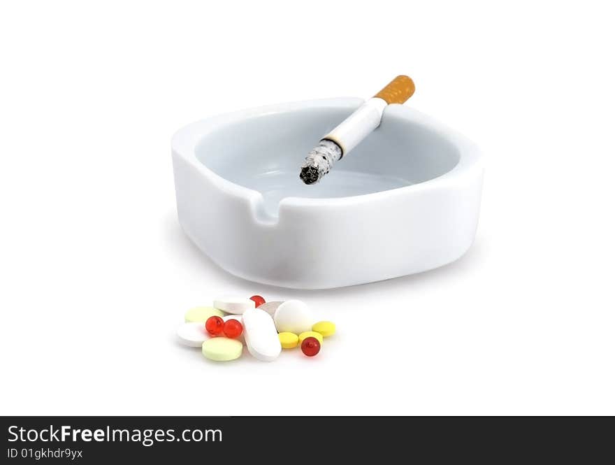 Decaying cigarette in an ashtray and tablets. Decaying cigarette in an ashtray and tablets.