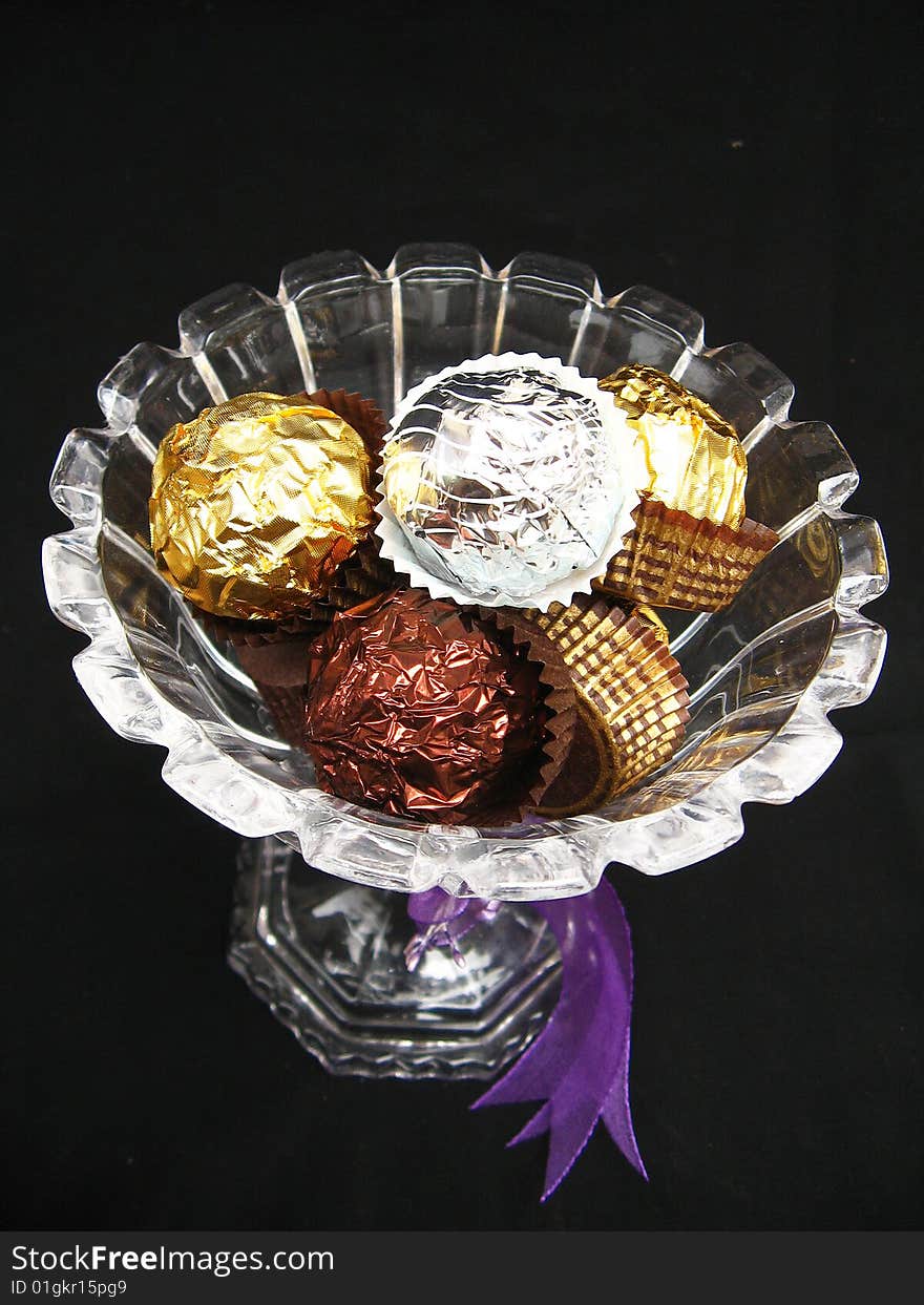 A gift of chocolate nuggets wrapped in different colored wrapping paper,in a bowl. A gift of chocolate nuggets wrapped in different colored wrapping paper,in a bowl