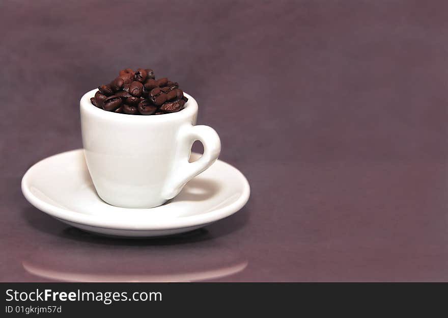 An espresso cup filled with roasted Colombian coffee beans.