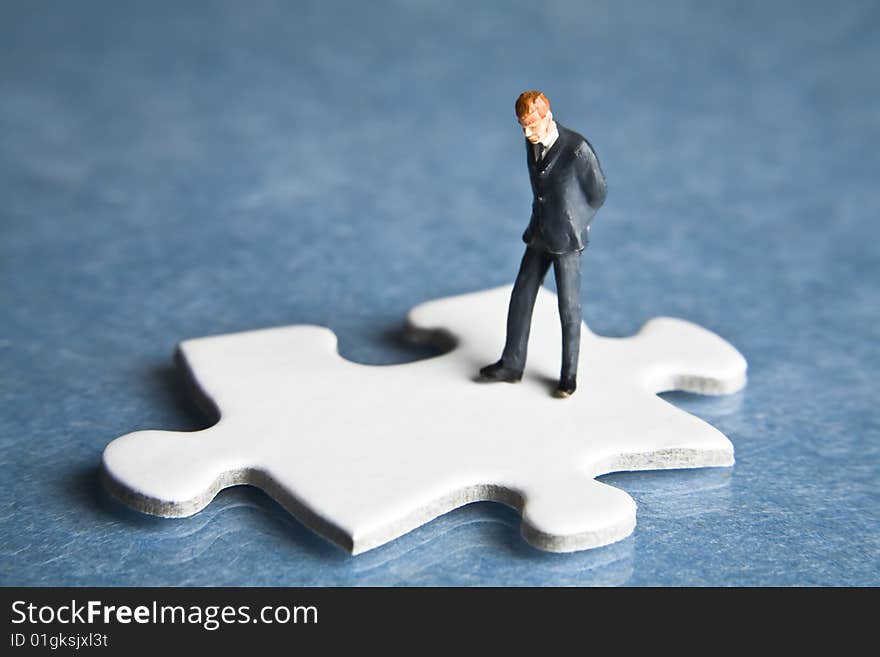 Businessman figurine placed on a puzzle piece. Businessman figurine placed on a puzzle piece