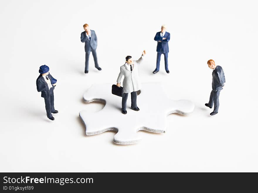 Five businessman figurines placed with a puzzle piece. Five businessman figurines placed with a puzzle piece