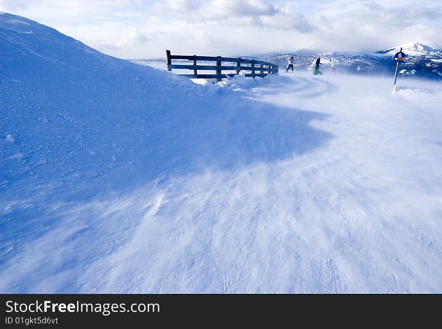 Snow covered mountain with few skiers in the background