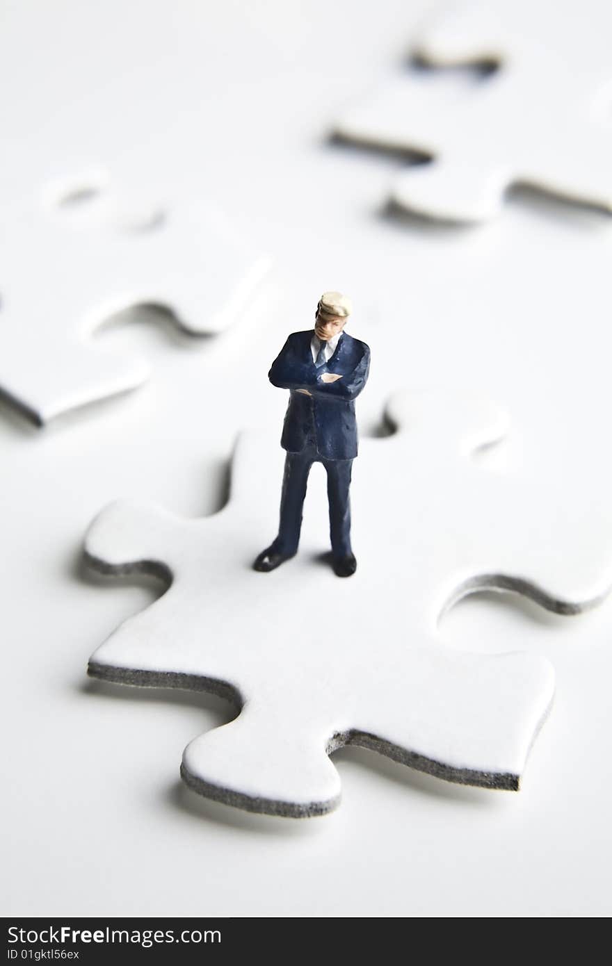 Businessman figurine placed on a puzzle piece. Businessman figurine placed on a puzzle piece