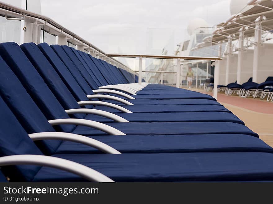 Blue chaise lounges lined up on the deck of a cruise ship. Blue chaise lounges lined up on the deck of a cruise ship