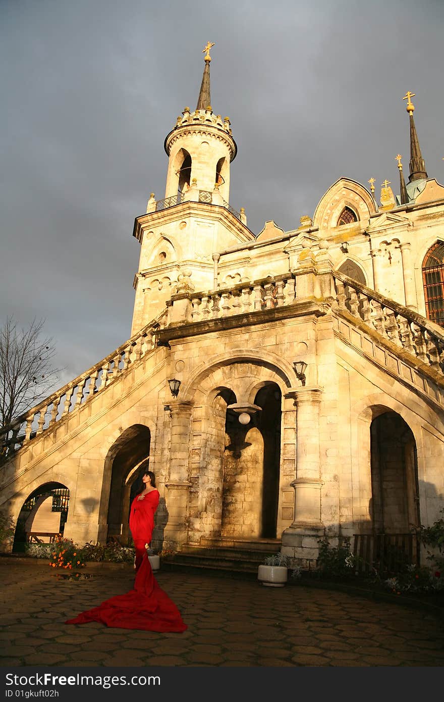 Lovely woman beside old castle in red fabric