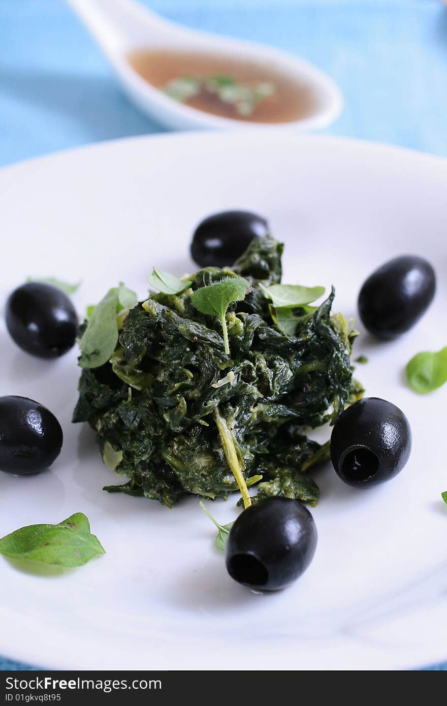 Spinach with black olives on blue background