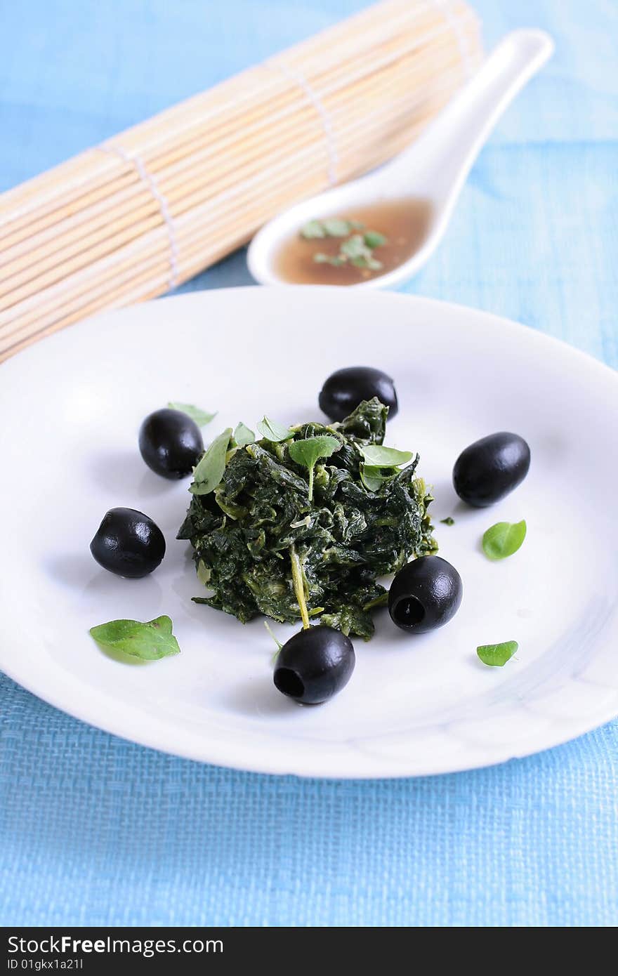 Spinach with black olives on blue background