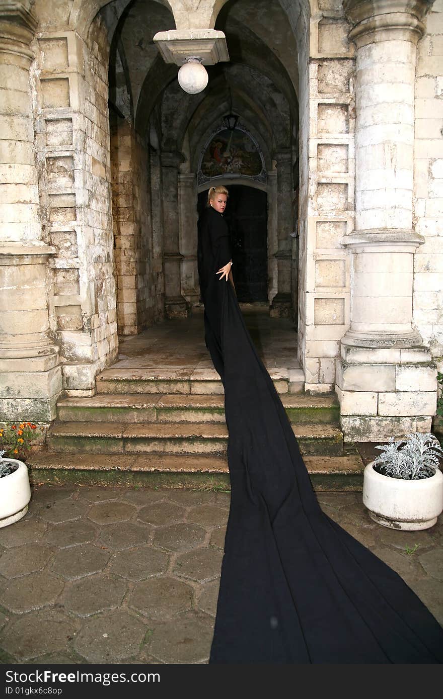 Lovely woman beside old castle in black fabric