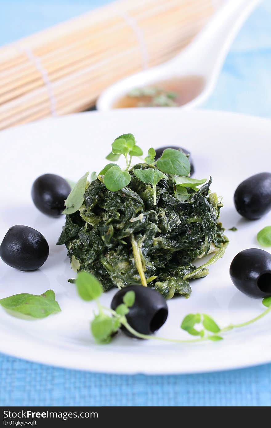 Spinach with black olives on blue background