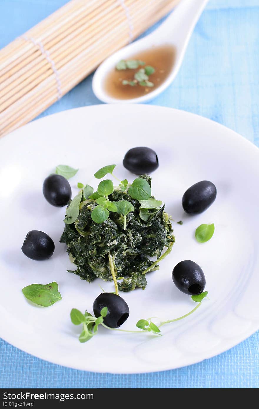 Spinach with black olives on blue background