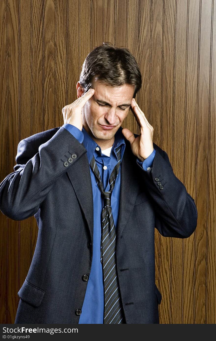 Businessman experiencing a headache rubbing his temples. Businessman experiencing a headache rubbing his temples