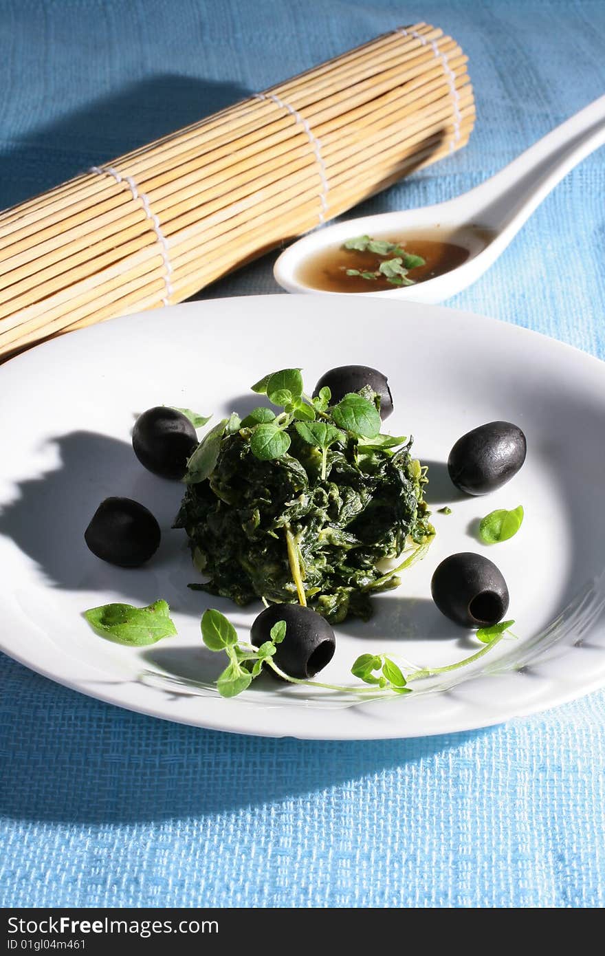 Spinach with black olives on blue background