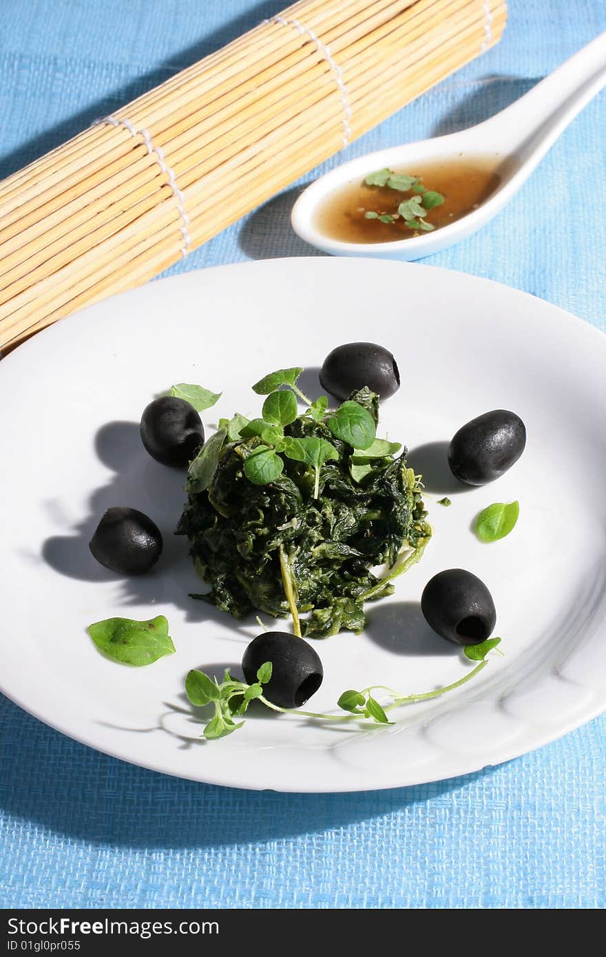 Spinach with black olives on blue background