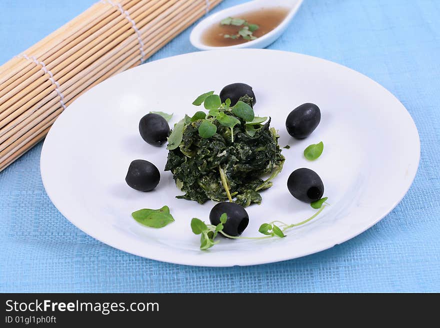 Spinach with black olives on blue background