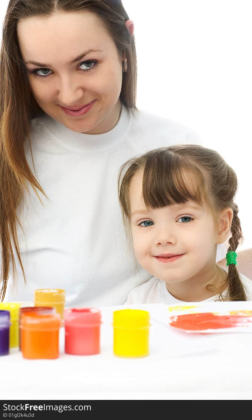 Young mother and her daughter sitting by the table and painting with watercolor. Young mother and her daughter sitting by the table and painting with watercolor