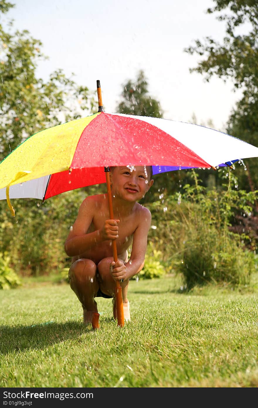 Little boy under umbrella in rain