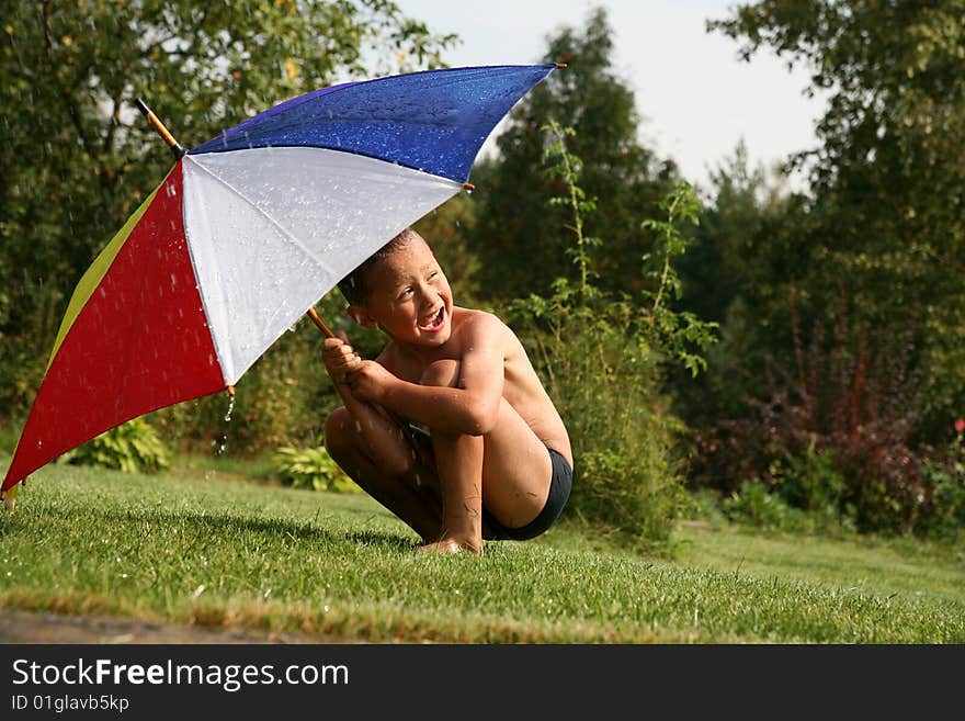 Boy under umbrella in summer rain