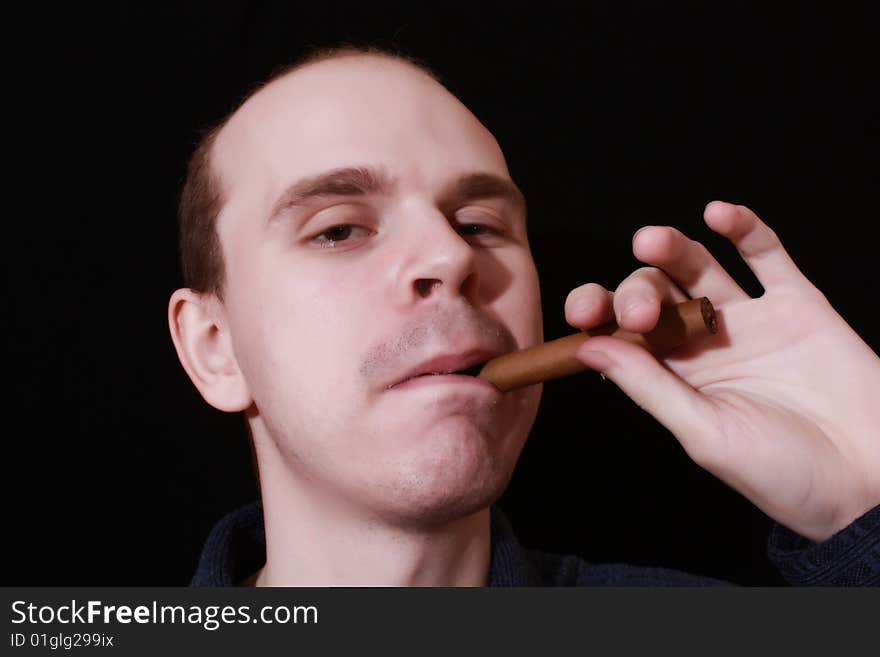 Young man with cigar on black background