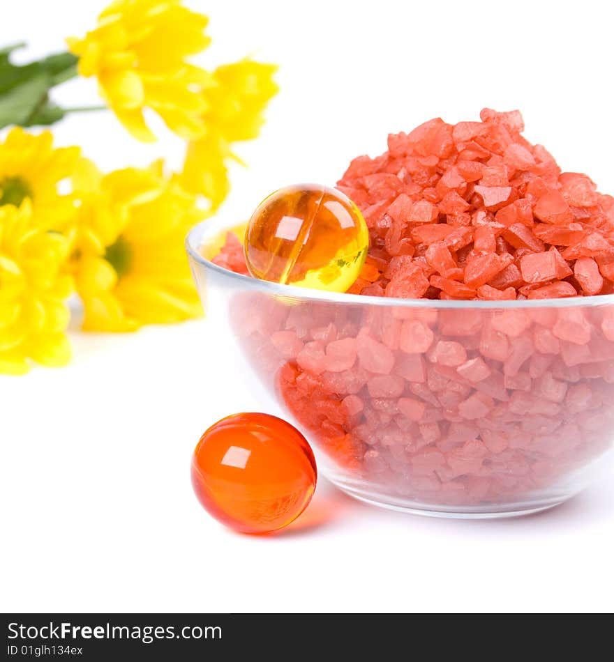 Spa pruducts: bath salt, oil balls in a bowl and yellow flowers