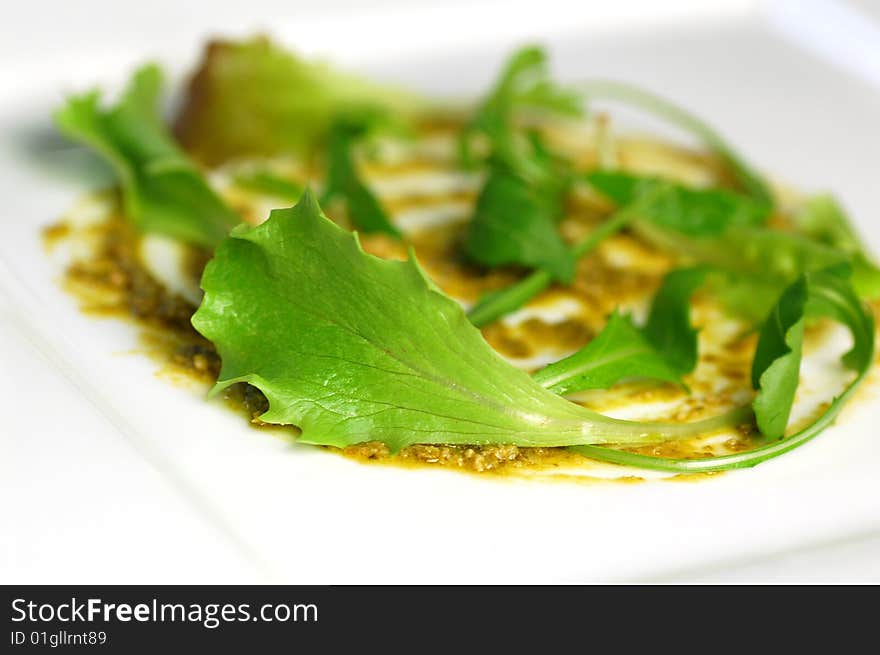 A plate dressed with pesto and salad.