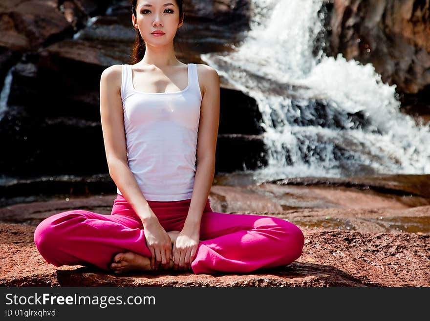 Young woman relaxing by the waterfall