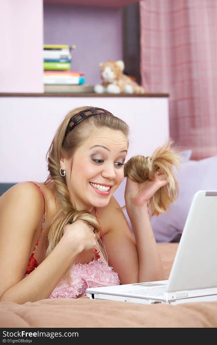 The surprised girl plays hair in front of the laptop. The surprised girl plays hair in front of the laptop