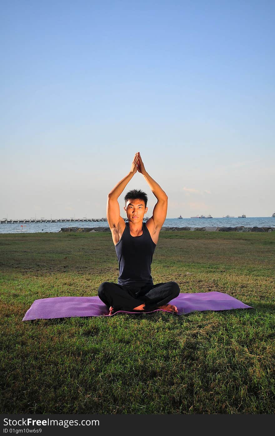 Picture of man doing yoga by the beach.