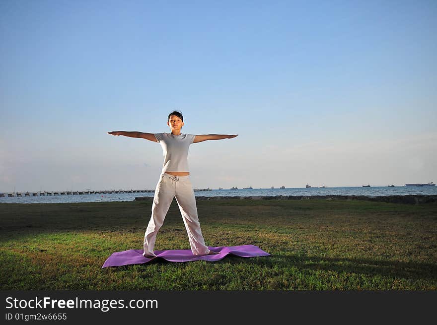 Picture of a woman doing yoga by the beach.