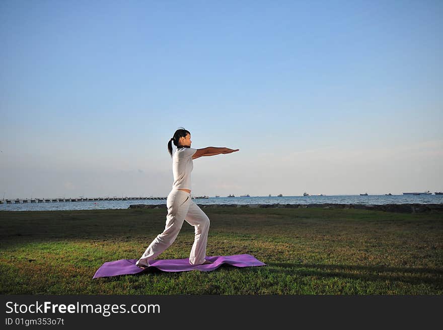 Picture of a woman doing yoga by the beach.