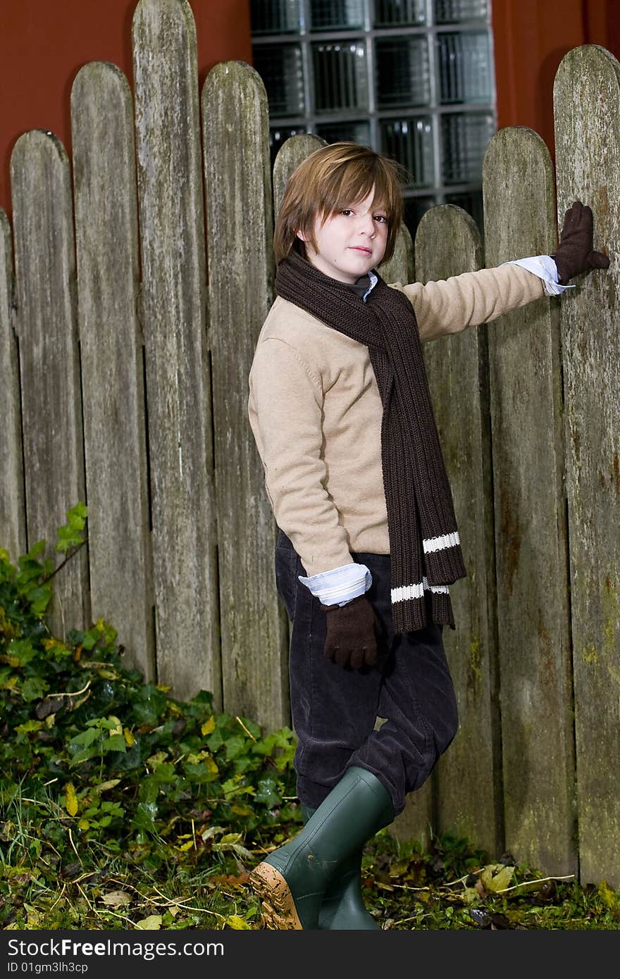 Cute young autumn boy standing near a fence. Cute young autumn boy standing near a fence