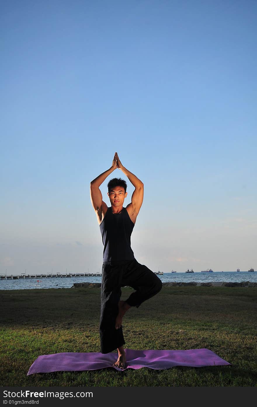 Picture of man doing yoga by the beach.