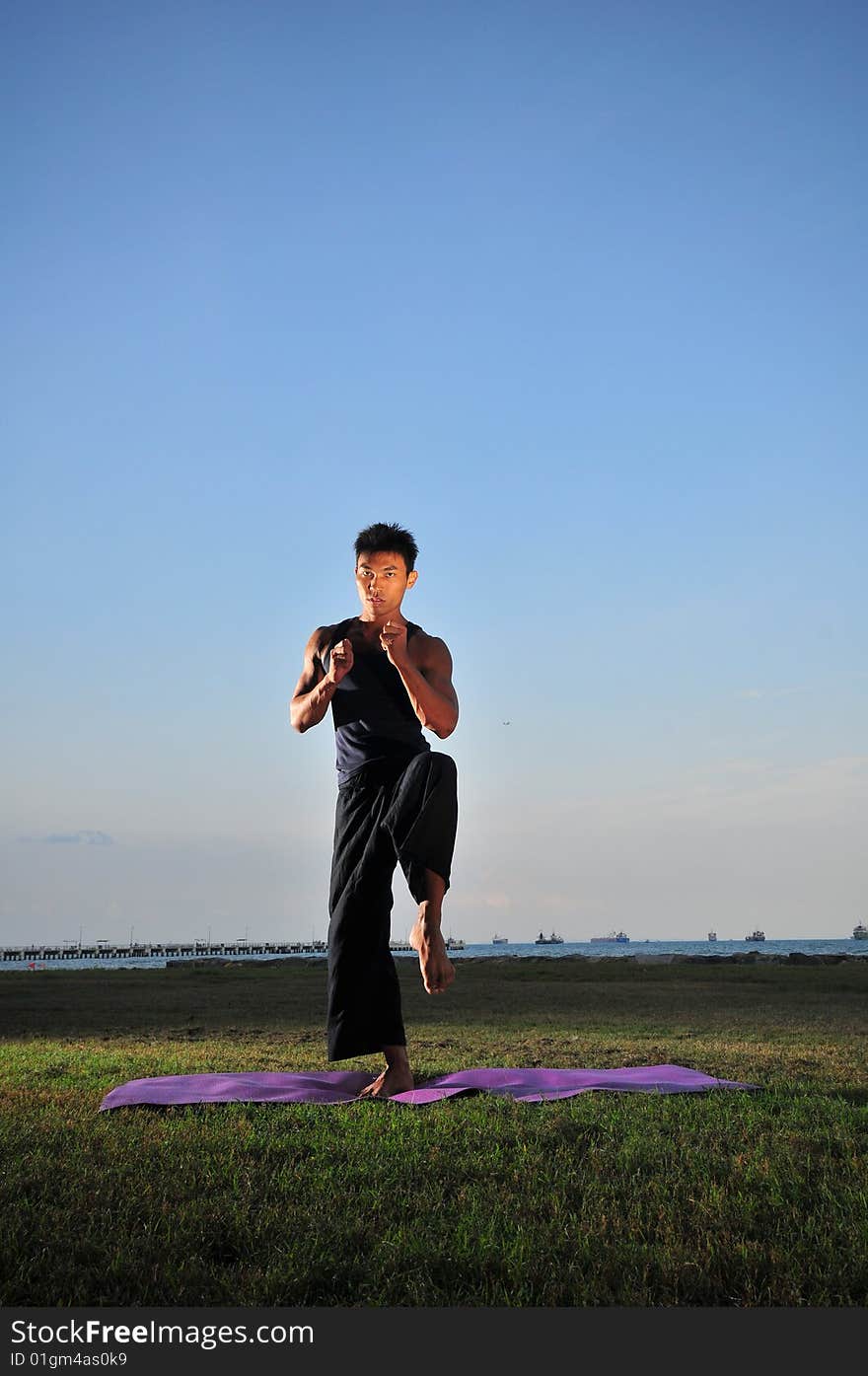 Picture of man doing yoga by the beach.