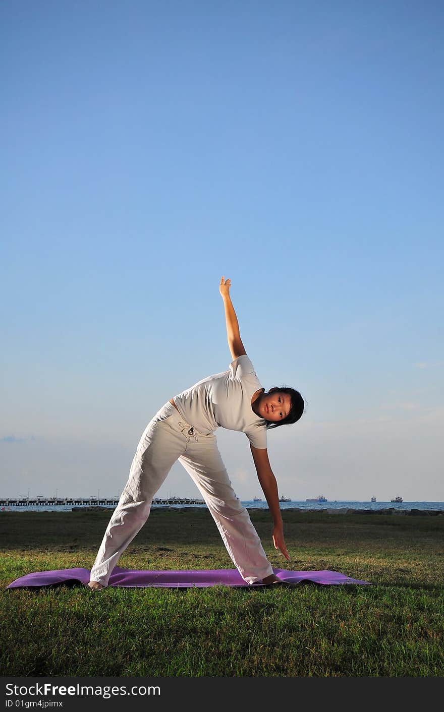 Picture of a woman doing yoga by the beach.