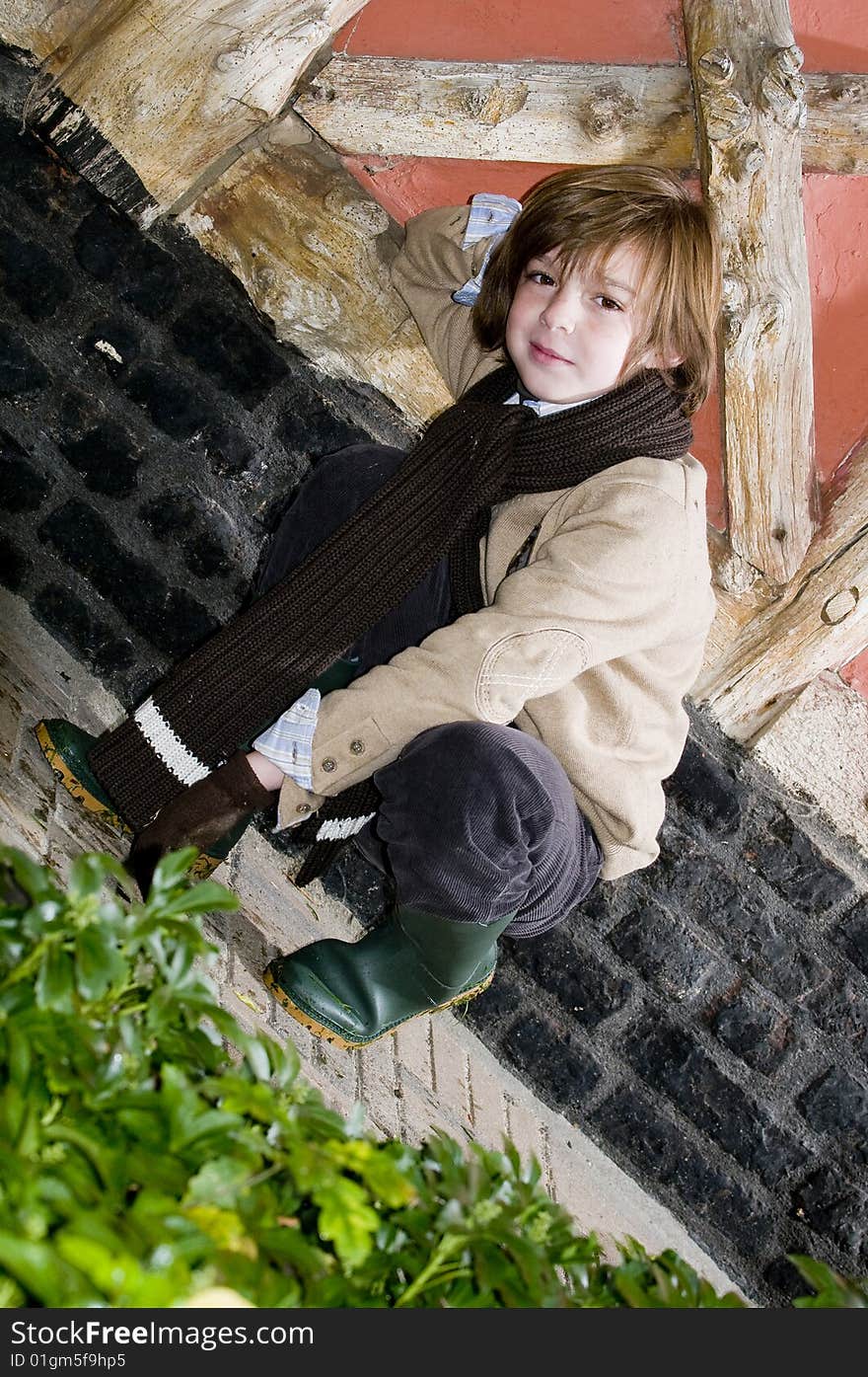 Cute young autumn boy standing near cottage. Cute young autumn boy standing near cottage