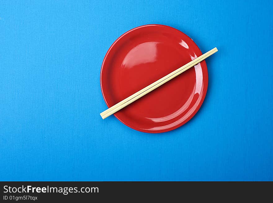 Red dish and chopsticks. Over blue table