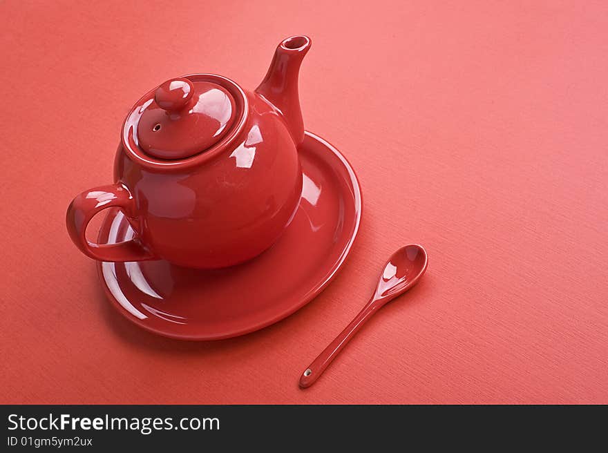 Teapot, cup and spoon on red table. Teapot, cup and spoon on red table