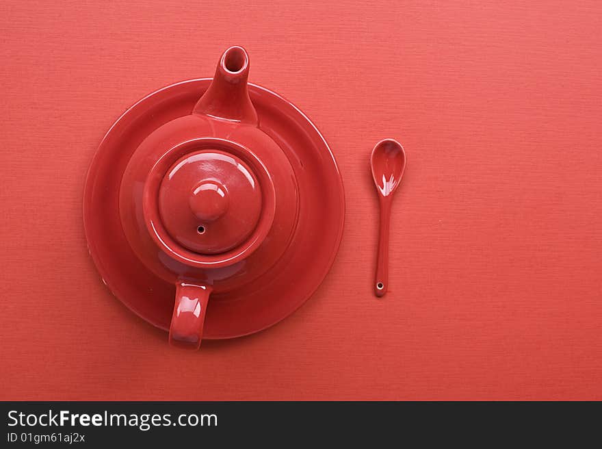 Teapot, cup and spoon on red table. Teapot, cup and spoon on red table