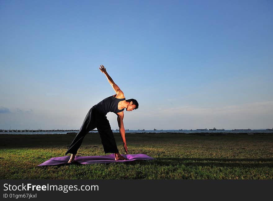 Picture of man doing yoga by the beach.