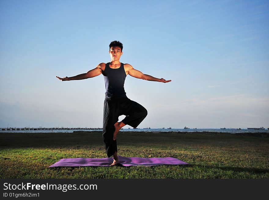 Picture of man doing yoga by the beach.