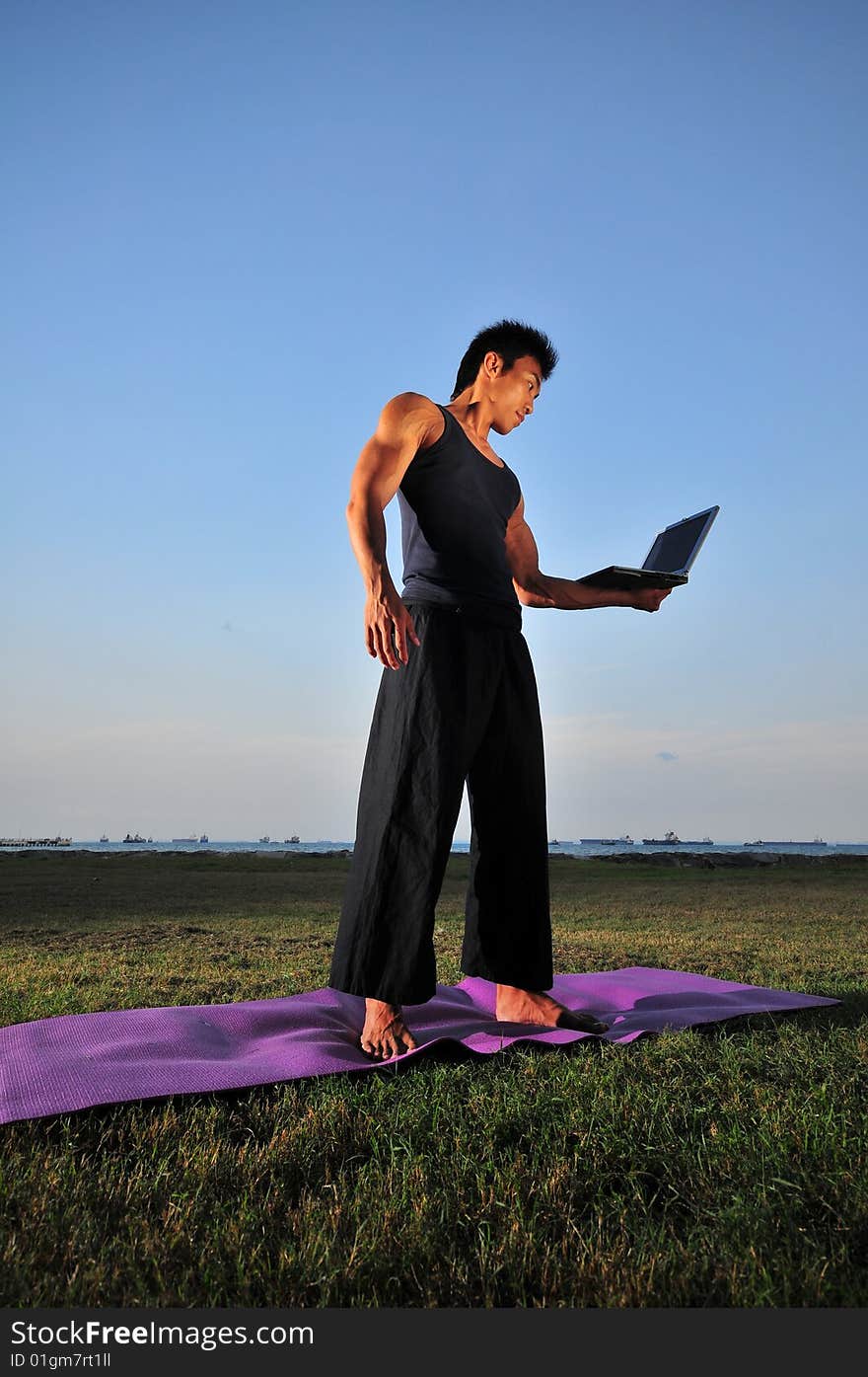 Picture of man doing yoga by the beach.