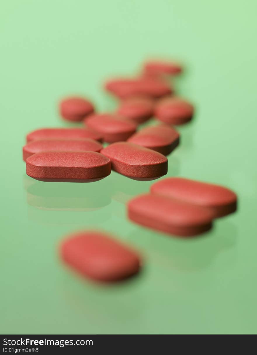 Red pills toward green background, pills, medical treatment, lozenge, tablet, pastille, pastil, drugs, curative, medicine, dietary supplements, vitamine, chemistry, dispensary, pharmacy, pharmaceutical chemistry, green, green background, studio, product, still life, still-life, red pill, red