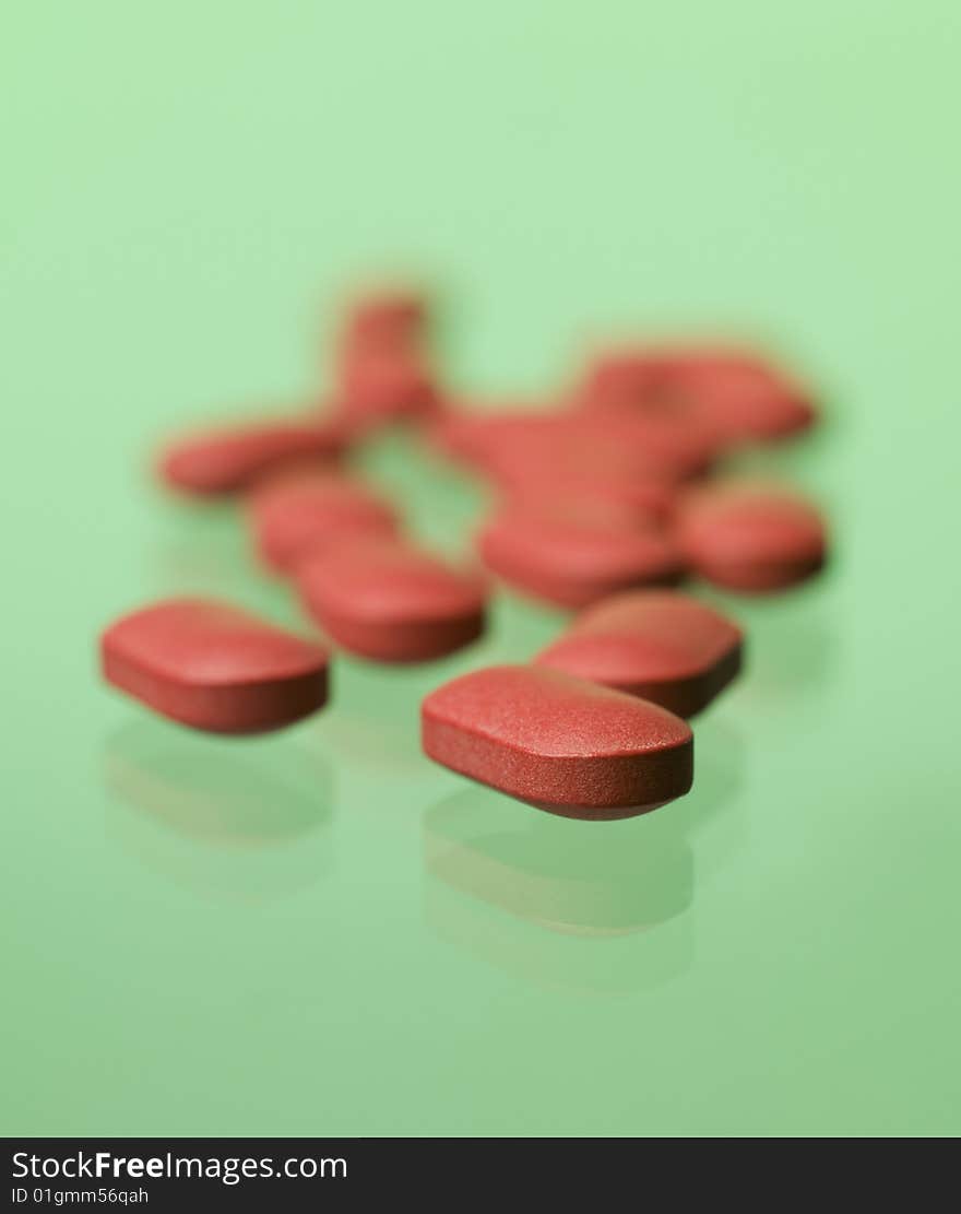 Red pills toward green background, pills, medical treatment, lozenge, tablet, pastille, pastil, drugs, curative, medicine, dietary supplements, vitamine, chemistry, dispensary, pharmacy, pharmaceutical chemistry, green, green background, studio, product, still life, still-life, red pill, red