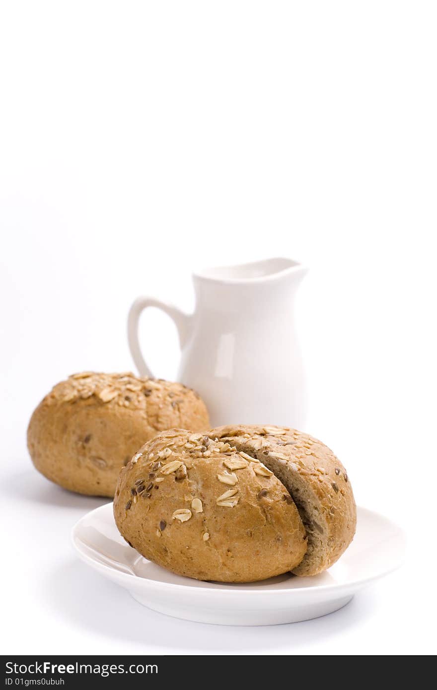 Bread and jug of milk on white background