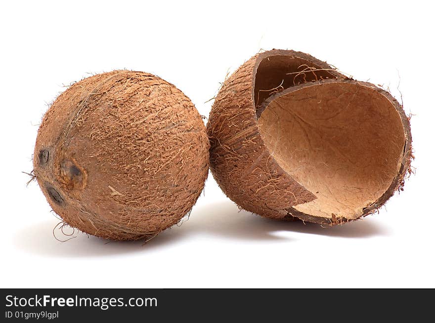 Whole and broken coconuts on a white.