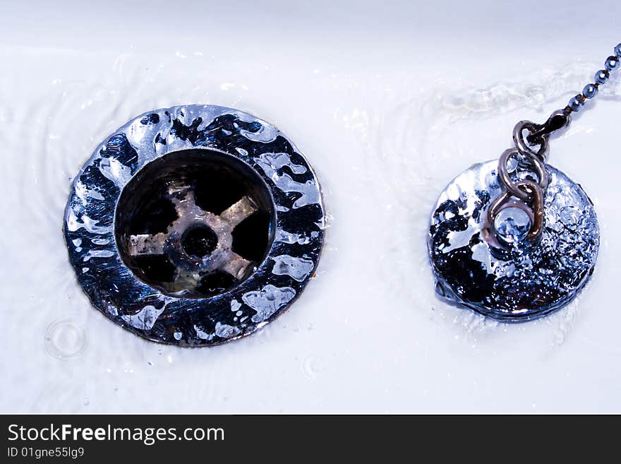 Sink and silver plug with water draining. Sink and silver plug with water draining